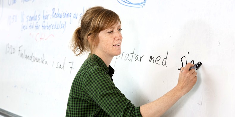 Kvindelig lærer skriver på tavle