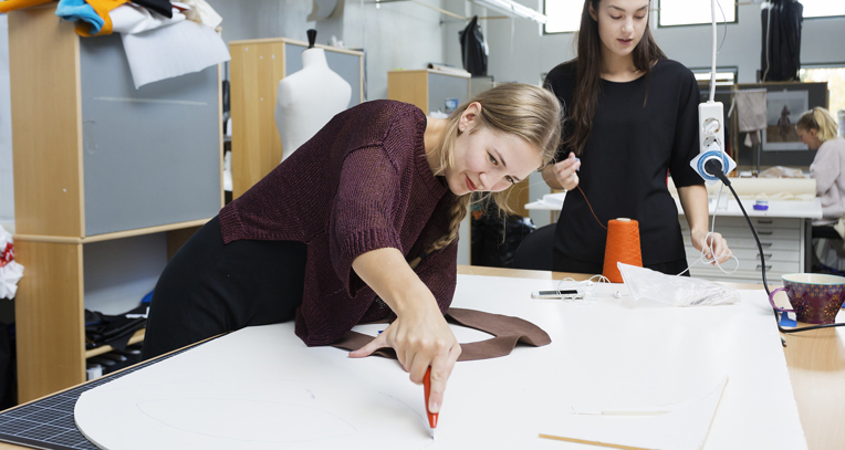 Kvindelig designstuderende udskærer mønster