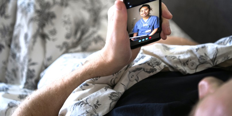 Syg mand i seng facetimer med kvindelig læge