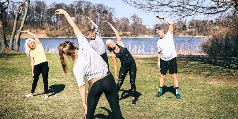 Fire ældre personer dyrker gymnastik i det fri med træner