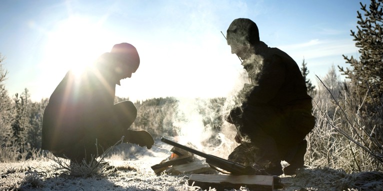 Jægere tænder bål i solbeskinnet skov