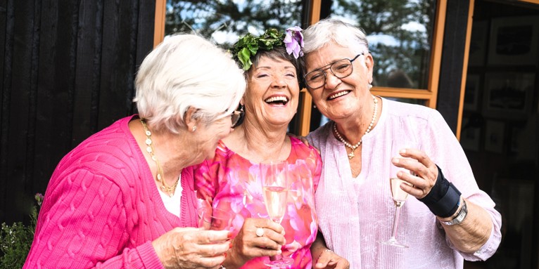 Tre grinende modne kvinder med champagneglas i hånden