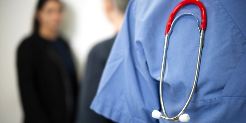 Anonym sundhedsmedarbejder i blå kittel med stetoskop om halsen