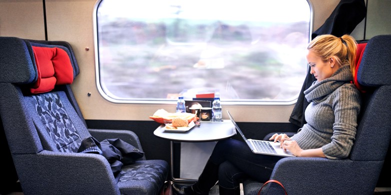 Kvindelig pendler i tog med computer på skødet